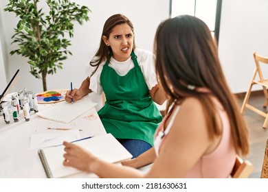 Two Latin Paint Students Arguing Sitting On The Table At Art School.