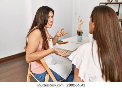 Two Latin Paint Students Arguing Sitting On The Table At Art School.