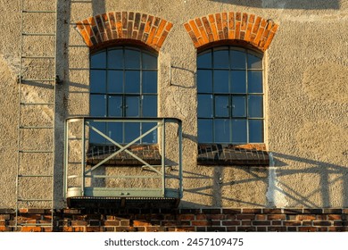 
Two lattice windows in an old warehouse in Bremen in the evening sunlight - next to them is a fire escape and a small balcony - Powered by Shutterstock