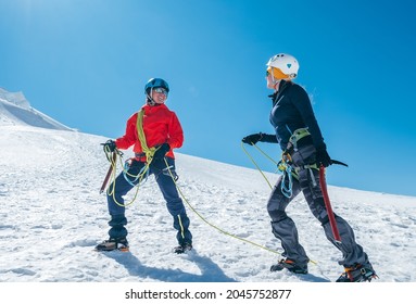Two Laughing To Each Other Young Women Rope Team Ascending Mont Blanc Du Tacul Summit 4248m Dressed Mountaineering Clothes With Ice Axes On Snowy Slopes. People Extreme Activities Sporty Concept Image