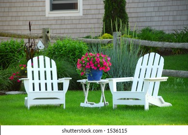 Two Lawn Chairs In A Beautiful Garden Near Cottage