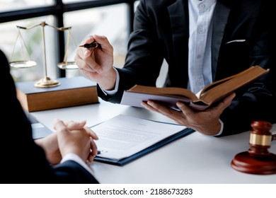 Two lawyers are reading a large book of law to jointly draft a prosecution contract and look at the details of the case for defending their clients. The concept of law and justice. - Shutterstock ID 2188673283
