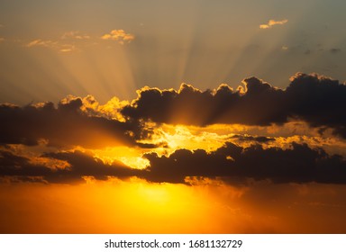 Two layers of clouds with sun shining behind leaving beautiful rays of sun from behind. Dramatic sunset sky with vibrant colors.