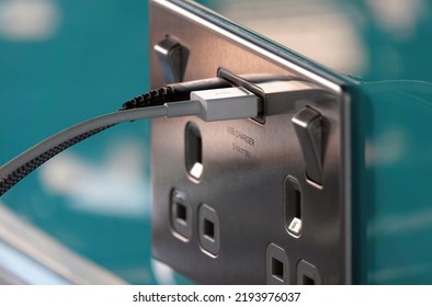 Two leads plugged into a USB charging point in an electric plug socket on a wall. 