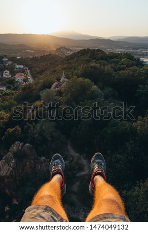 Two legs hanging on the heights overlooking a beautiful sunset in Palafolls, Spain