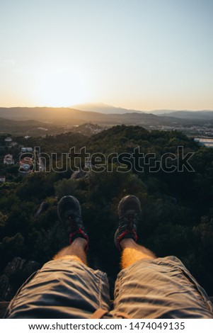 Two legs hanging on the heights overlooking a beautiful sunset in Palafolls, Spain