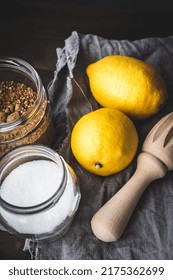 Two lemons, two glass jars with sugar and a lemon wooden squeezer