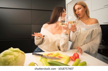 Two Lesbian Female Friends Making Salad In The Kitchen And Drinking Wine From A Wine Glasses. Life Stile Concept. Healthy Food