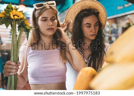 Two lesbian women choosing tropical fruit on fruit market in Chiang Mai