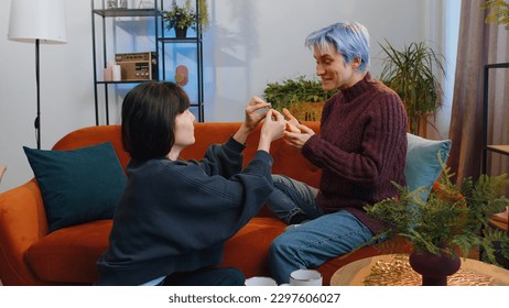 Two lesbian women family couple. Homosexual female girl gay making a surprise engagement ring love proposal of marriage to her beloved woman. Accepting emotionally say yes. LGBT people at home room