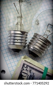 Two Light Bulbs Old Next To A Block Of Tickets Of Dollar, Concept Of Saving Energy