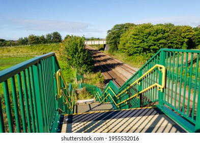 A two line section of railway track with a metal road bridge, seen from an unusual high viewpoint on a pedestrian footbridge