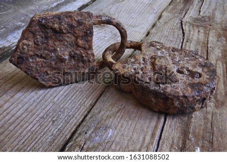 Two linked old rusty padlocks symbolizing good relationships or marriage. Old rusty padlocks on old wooden table close-up. Selective focus.