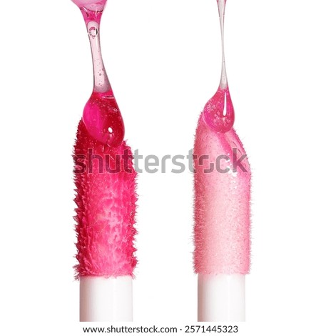 Two lip gloss applicators. Drops of liquid lip gloss falls on applicators. Closeup shot, isolated on white                               