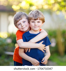 Two little active school kids boys, twins and siblings hugging on summer day. Cute brothers, preschool children and best friends portrait. Family, love, bonding concept