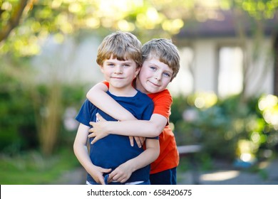 Two little active school kids boys, twins and siblings hugging on summer day. Cute brothers, preschool children and best friends portrait. Family, love, bonding concept.