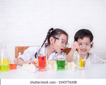 Two little Asian cute girl role playing a scientist. The experiment of water transport with colors into cabbage. The first step, dropping food coloring into the water. Learning and education of kid.