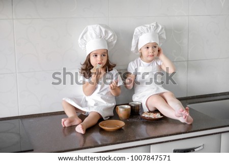 two little baker girls are drinking tea with a pabcakes in the kitchen