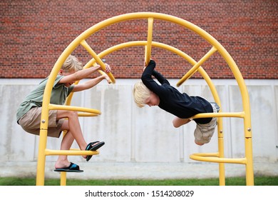 Two little boy children are playing outside of the school at the playground, climbing on jungle gym bars. - Powered by Shutterstock
