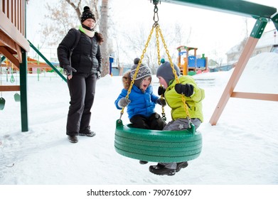 Two little boy ride on a swing on the Playground in winter. - Powered by Shutterstock