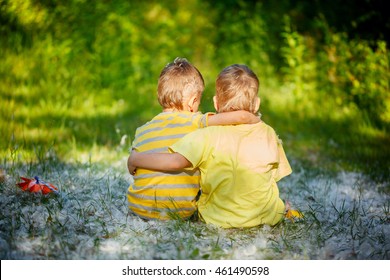 Two Little Boys Friends Hug Each Other In Summer  Garden. Brother Love. Concept Friendship. Back View.