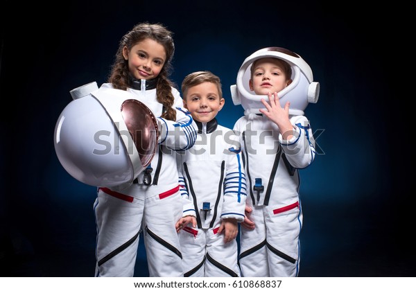 宇宙服を着た2人の少年と女の子が カメラを見ている宇宙飛行士を演じている の写真素材 今すぐ編集