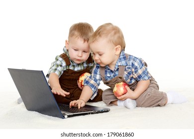 Two little boys with  with notebook and fresh apples sit on a floor on a white background.