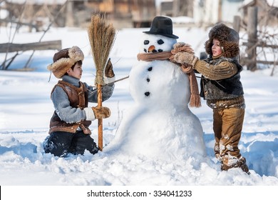 Two Little Boys Sculpt A Snowman In The Backyard Of The House Clear Winter Day