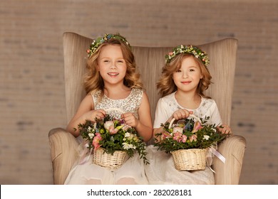 two little bridesmaid sitting in a chair with bouquets