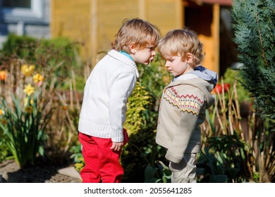 Two little brothers boys fighting and having dispute. Preschool, upset children arguing outdoors. Rivalry and competition betweens siblings. Unhappy twins. One boy crying