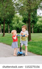 Two Little Caucasian Preschool Children Fighting In Park Outside. Boy And Girl Can Not Share One Scooter. Older Sibling Brother Not Giving His Toy To Younger Sister. Communication Problems.