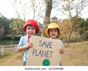 Two little child girl siblings holding "Save the planet" Poster showing a sign protesting against plastic pollution in the forest. The concept of World Environment Day. Zero waste.