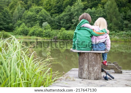 Two little child hug each other and look a the lake view