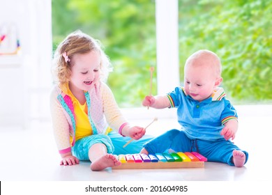 Two little children, brother and sister, cute curly toddler girl and a funny baby boy, having fun with colorful xylophone at a window, kids early development class, playing music - Powered by Shutterstock
