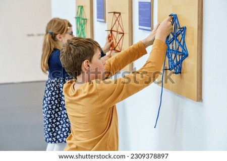 Two little children playing logical games indoor. Boy and little girl having fun with building and creating geometric figures. with strings in child museum for maths