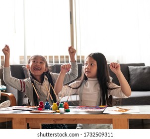 Two Little Girl Raise Hands Up In The Air With Happy Feeling,after Finish Painting Work.blurry Light Around