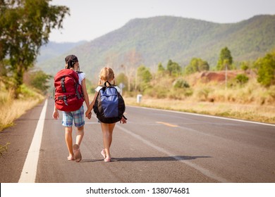 two little girls with backpack walking on the road