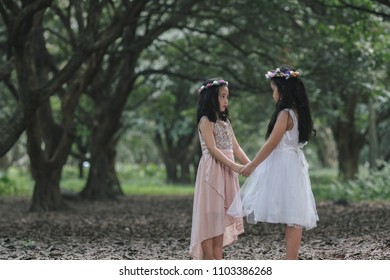 Two little girls in a beautiful dress in a park at sunset in Hanoi, Vietnam.