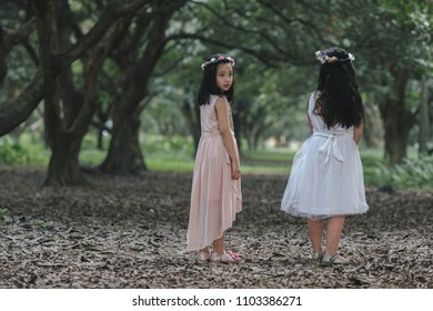 Two little girls in a beautiful dress in a park at sunset in Hanoi, Vietnam.