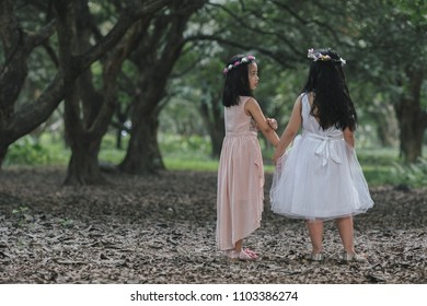 Two little girls in a beautiful dress in a park at sunset in Hanoi, Vietnam.