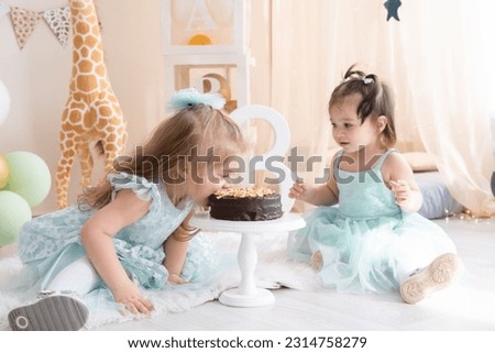 Two little girls in blue dresses eating chocolate birthday cake