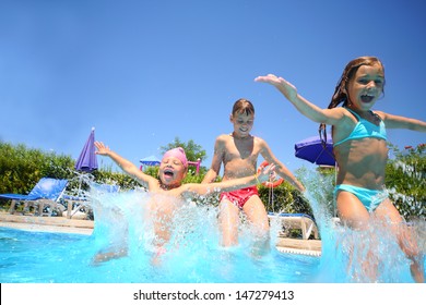Two little girls and boy fun jumping into the swimming pool, shot through the underwater package