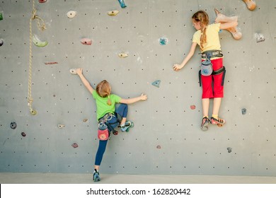 two little girls climbing a rock wall