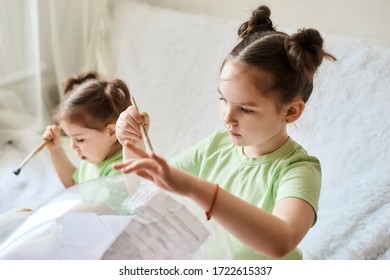 Two Little Girls With Dark Hair And Light Skin In Light Green Make A Paper Mache Craft