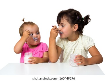 two little girls eating yogurt isolated on white