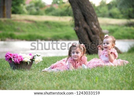 Two little girls in pink dresses on a river banks. Little sister play outside