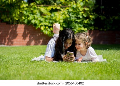 two little girls are playing on the lawn in the garden of their house.
