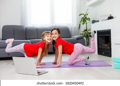 Two Little Girls Practicing Yoga, Stretching, Fitness By Video On Notebook. Distant Online Education Training, Aerobic At Home. Healthy Lifestyle, Coronavirus, Stay Home. Kids Sport Home Quarantine.