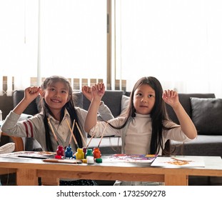 Two Little Girls Raise Hands Up In The Air With Happy Feeling,after Finish Painting Work.blurry Light Around