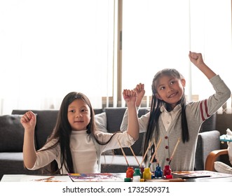 Two Little Girls Raise Hands Up In The Air With Happy Feeling,after Finish Painting Work.blurry Light Around